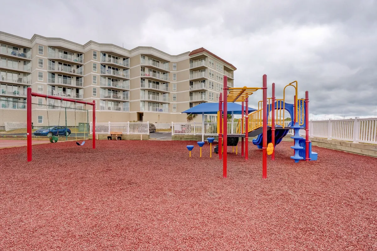 A cheerful, colorful playground with swings and play structures designed for children, with families and kids enjoying outdoor playtime.