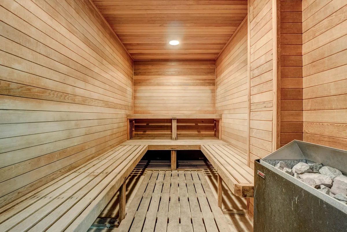 A serene interior shot of a wooden sauna with warm bench seating and a sauna heater, inviting relaxation and wellness after a day of activity.