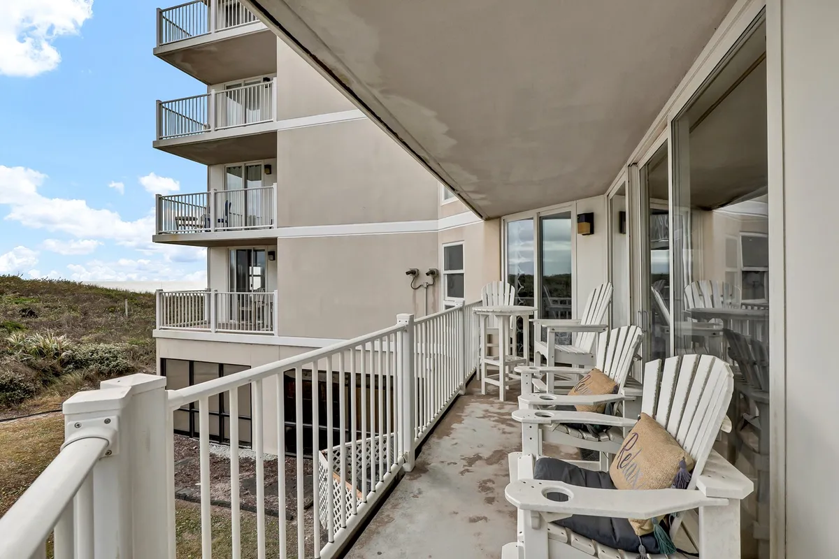 An inviting balcony with comfortable seating overlooks the landscape, with the building structure visible in the background. This vantage point suggests a serene spot to enjoy the sunrise or unwind after a day of activities, connecting the private condo experience to the outdoors.