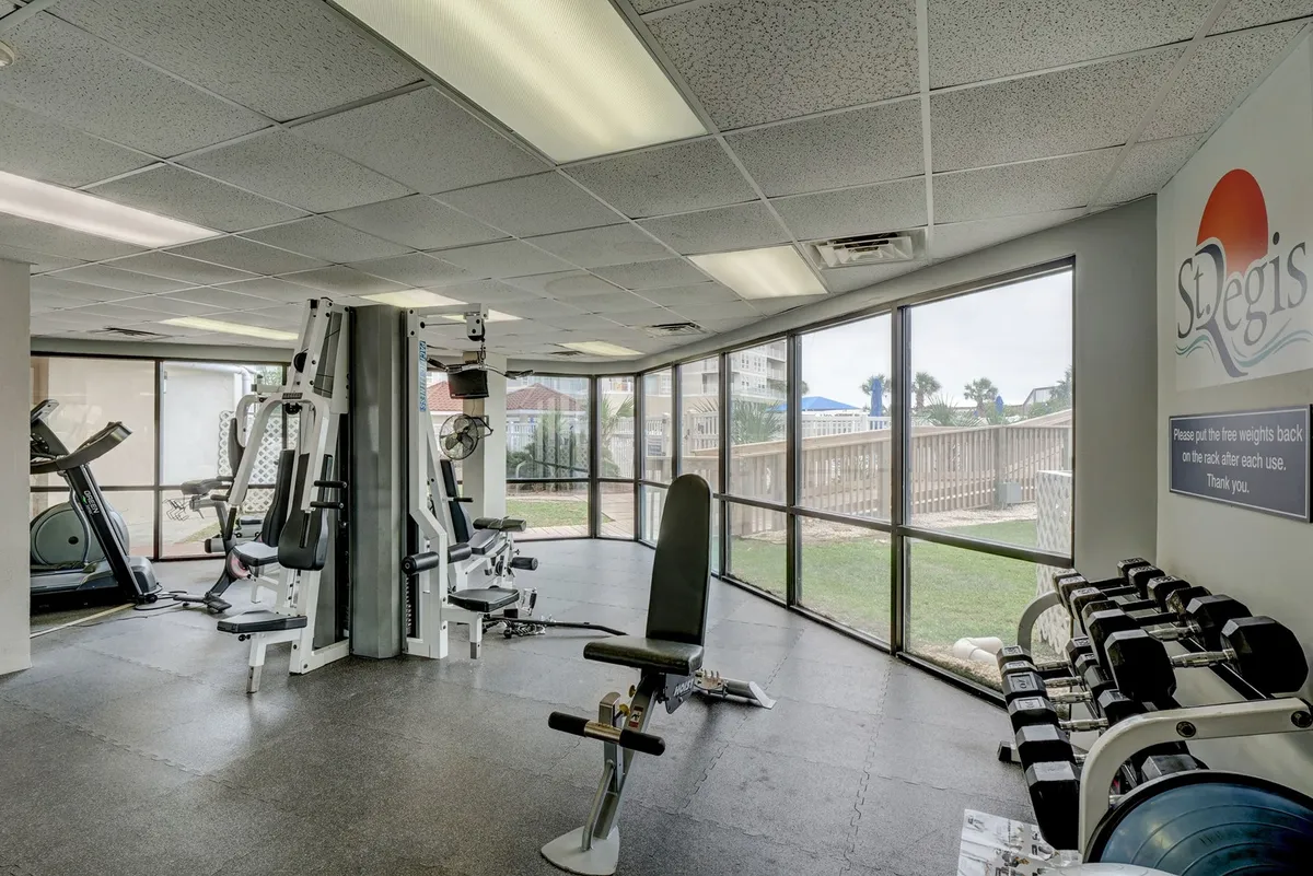 A modern fitness center with exercise machines, weights, and large windows letting in abundant natural light. The energetic, motivational setting is ideal for fitness routines, group classes, or solo workouts.